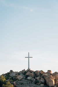 Cross on rock against sky