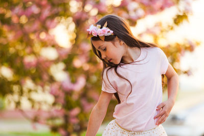 Smiling girl standing against flowering tree