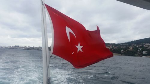 Red flag in sea against sky