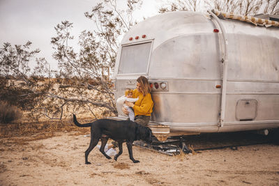 A woman with a baby and a dog is near an rv trailer, california