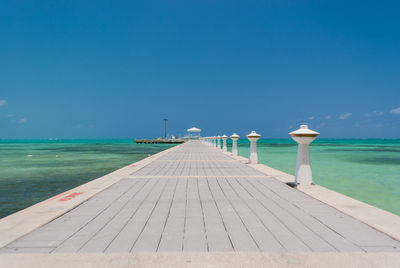 Pier over sea against clear blue sky
