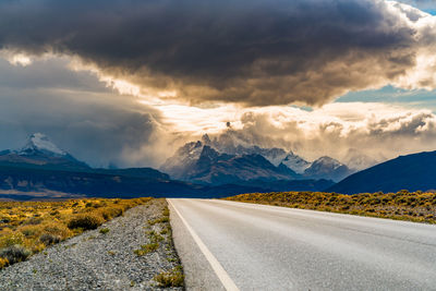 Road leading towards mountains against sky