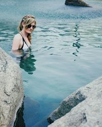 Young woman wearing sunglasses swimming in lake