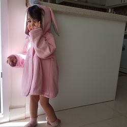 Full length of woman standing against pink wall at home