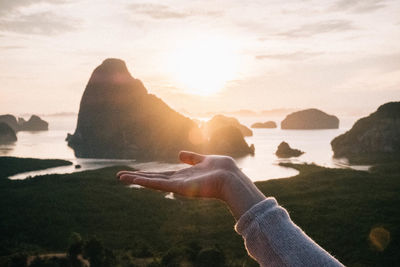 Midsection of man on rock at beach against sky