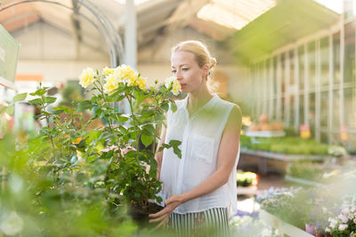 Woman looking at camera while standing by plants
