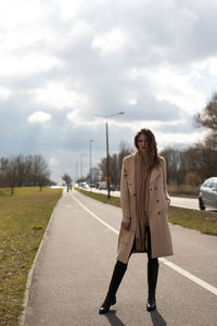 Portrait of young woman standing on road against sky