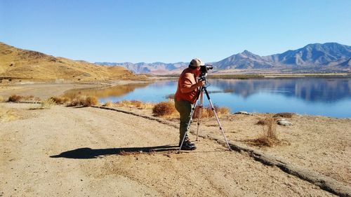 Photographer photographing lake through camera