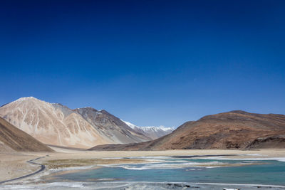 Scenic view of snowcapped mountains against blue sky