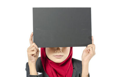 Portrait of woman holding hat against white background