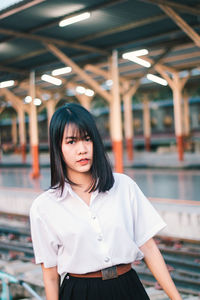 Portrait of young woman standing against wall