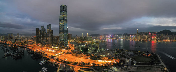 Illuminated buildings by river against sky at night
