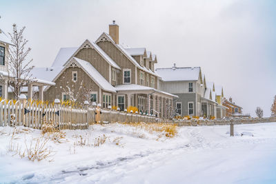 Buildings on snow covered field against sky