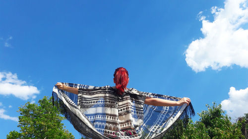 Low angle view of a woman against blue sky