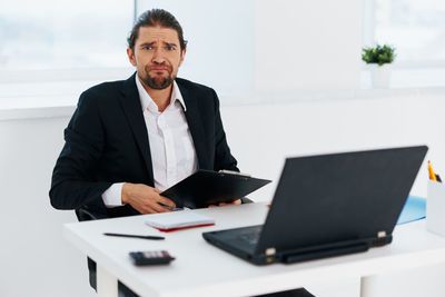 Portrait of businessman using laptop on table