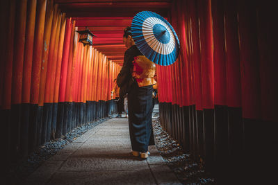 Rear view of woman standing with umbrella