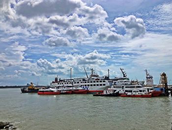 Fishing boats on pier by sea against sky