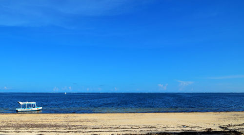 Scenic view of beach against clear blue sky