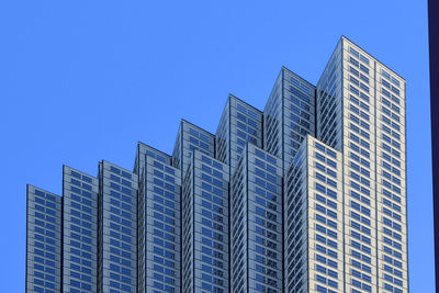 Low angle view of modern buildings against clear blue sky