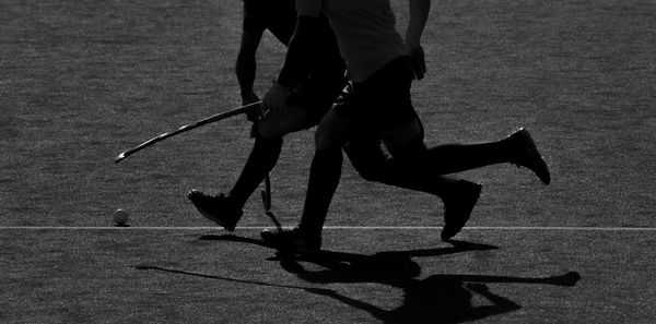 Low section of people playing hockey on field