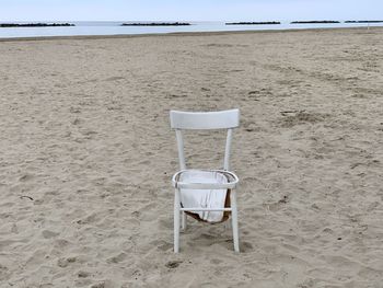 Empy beach with an abandoned and broken wooden chair