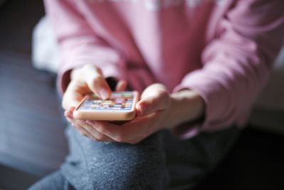 Midsection of woman holding camera while sitting at home