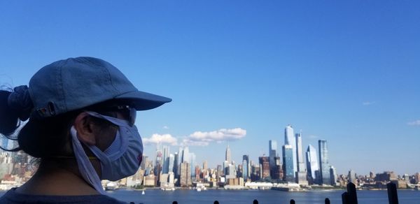 Rear view of man in city against blue sky