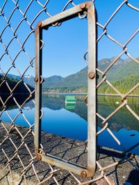 Scenic view of lake seen through chainlink fence