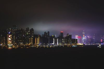 Illuminated buildings in city against sky at night