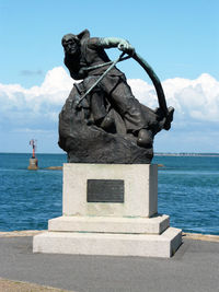 Statue by sea against sky