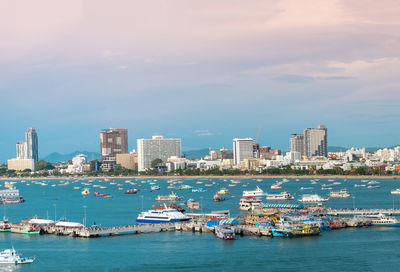 Boats in sea by buildings in city against sky