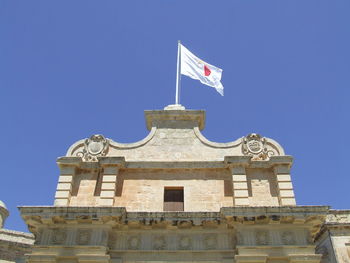 Low angle view of flag on building against clear blue sky