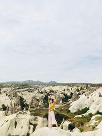 Woman standing on rock against sky