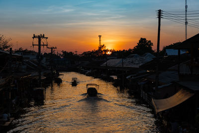 Silhouette sailboats moored in canal against sky during sunset