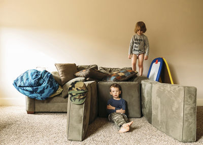 Portrait of boy relaxing while brother standing on sofa