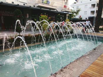 People in swimming pool against buildings in city