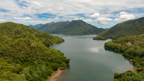 Mountain lake among hills with tropical vegetation and blue sky with clouds. 