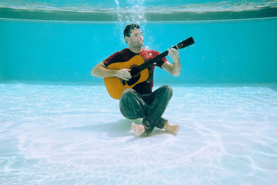 Man playing guitar in swimming pool