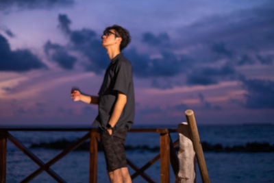 Side view of man looking at sea against sky