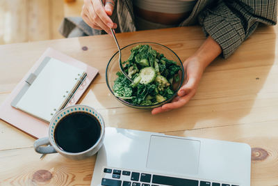 Midsection of woman using laptop on table