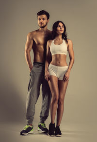 Young athletic man and woman standing against white background