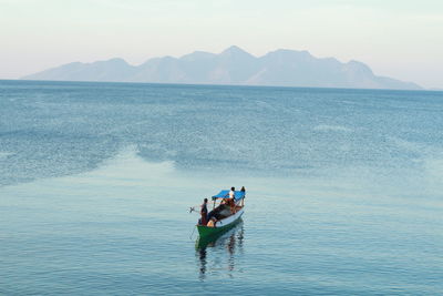 People on boat in sea against sky