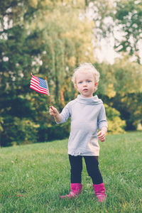 Portrait of girl holding american flag standing on land