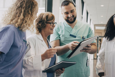 Smiling multiracial medical team discussing over clipboard at hospital