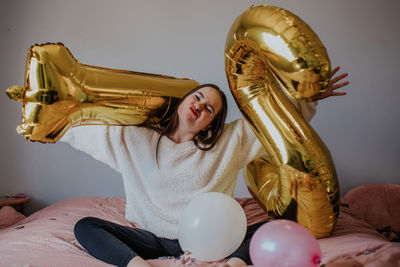 Woman sitting on balloons at home