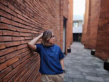 Portrait of young woman standing against wall