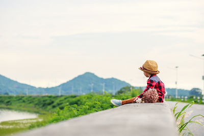 Woman sitting on land against mountain