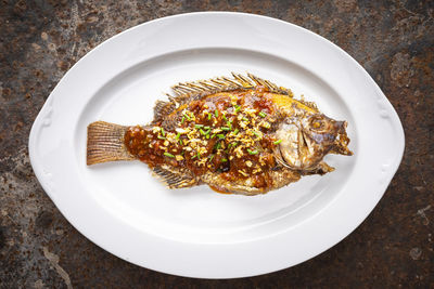 Tasty large deedp fried nile tilapia fish with chlli sauce, fried garlic and sliced spring onion