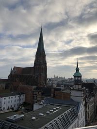 Buildings in city against cloudy sky