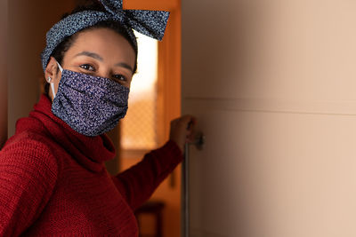 Portrait of woman wearing mask standing at home